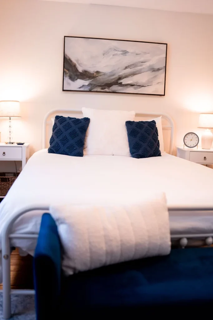 Bedroom in this 3-bedroom vacation rental in South Haven, with a white bed, gray headboard, and navy pillows.